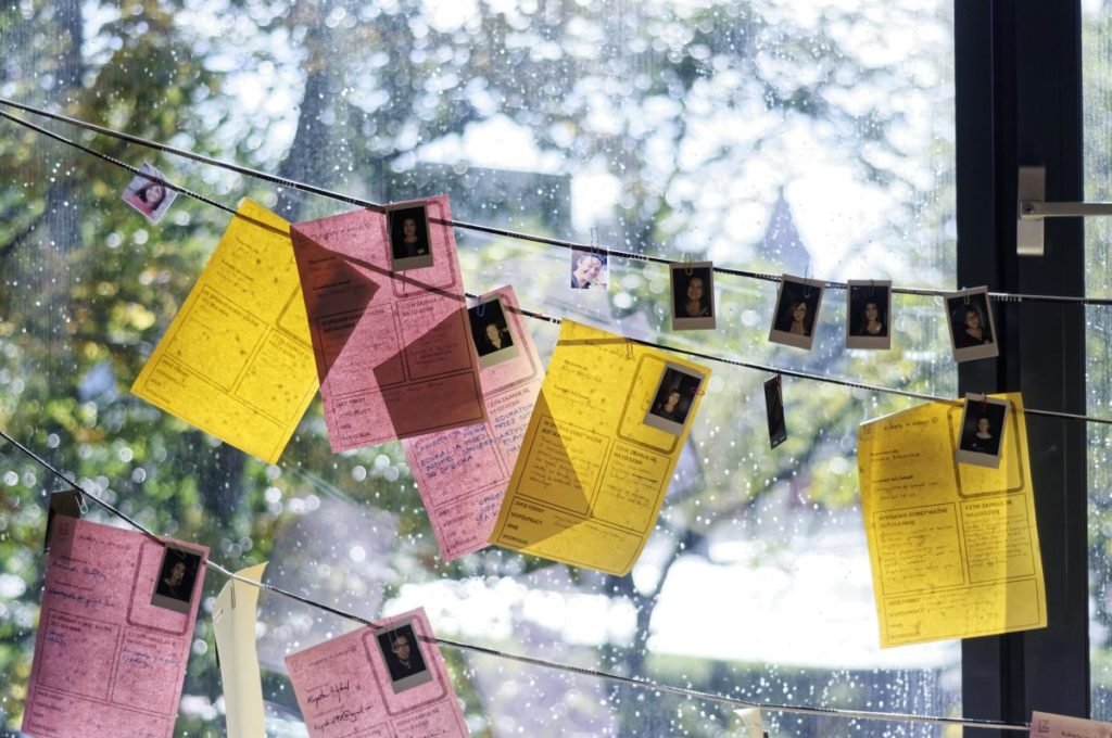 zawieszone na sznurkach zdjęcia oraz kartki papieru