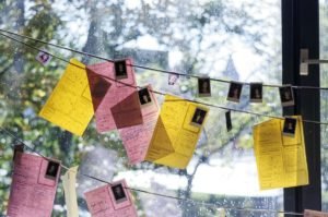 zawieszone na sznurkach zdjęcia oraz kartki papieru