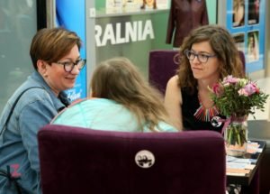 trzy kobiety prowadzą rozmowę siedząc na krzesłach