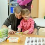 mała dziewczynka układa z tatą puzzle