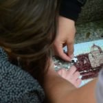 Na zdjęciu dłonie trzech osób układające puzzle z wizerunkiem bazyliki.