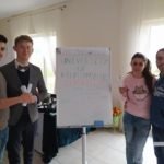 cztery osoby przy stojaku do prezentacji