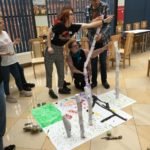 kilka piramid z plastikowych kubków i kartek papieru zwiniętych w rulon